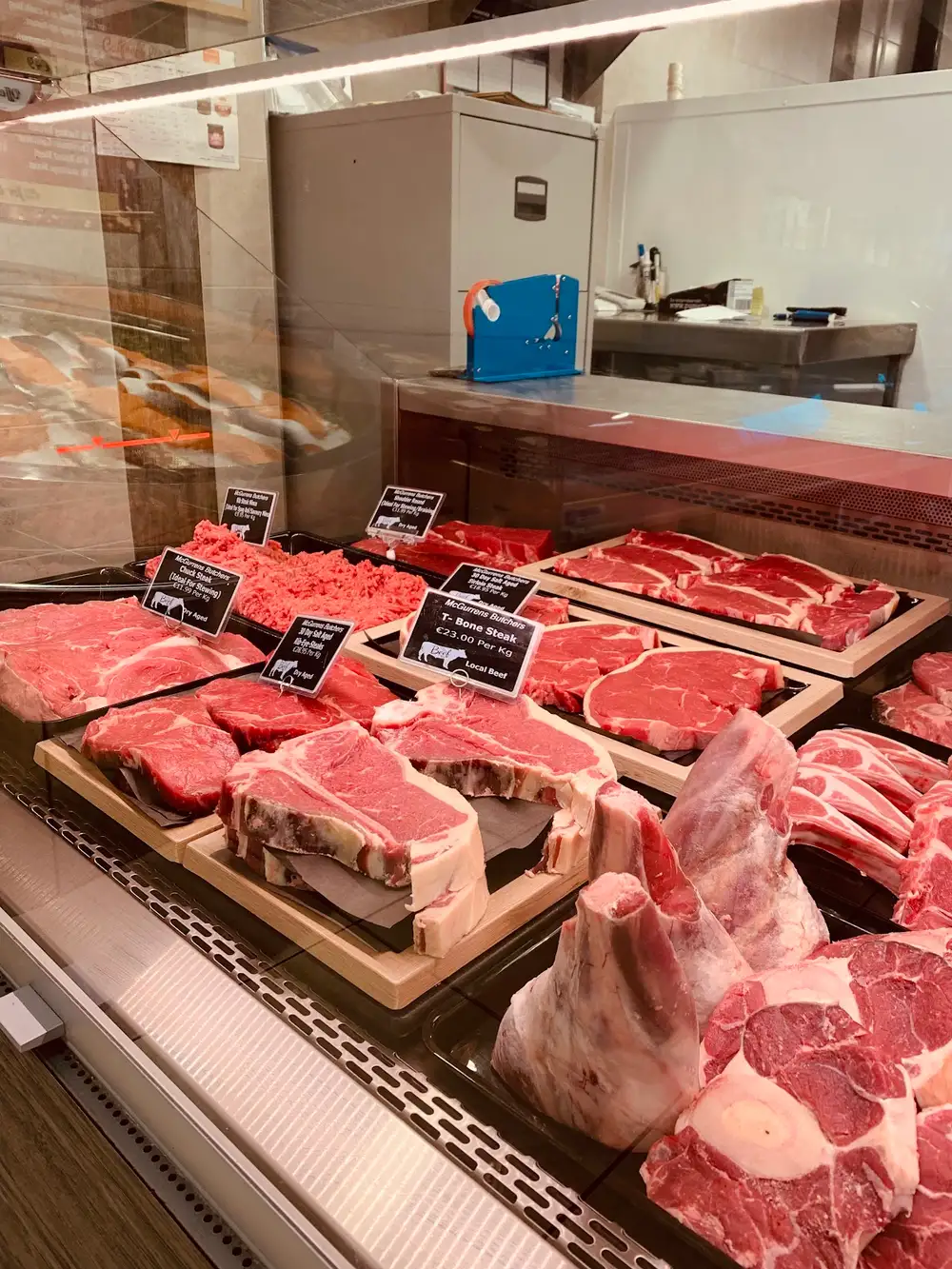 T-bone steaks and rib roasts on wooden boards in the beef counter, tagged Local Beef